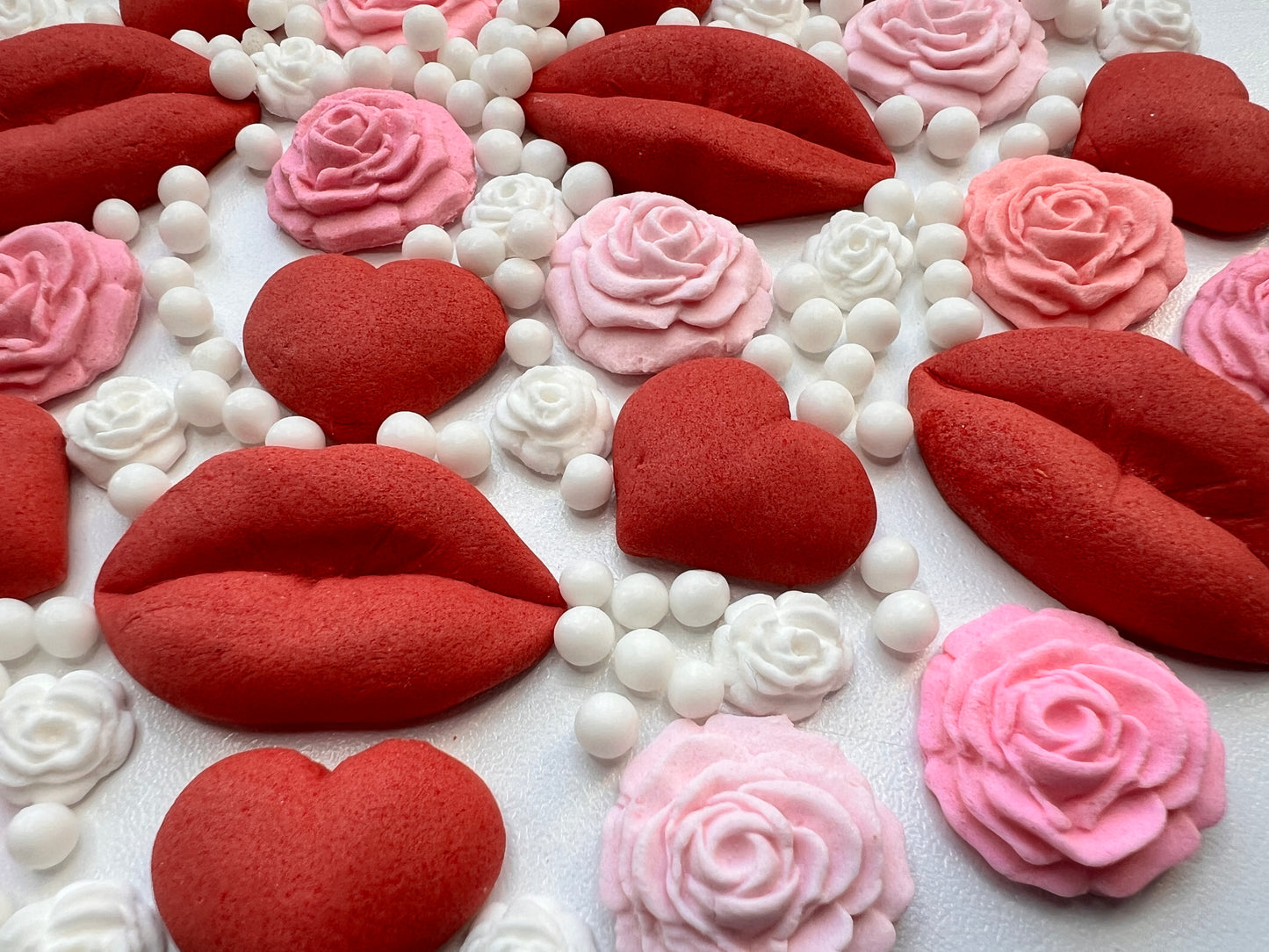 cake toppers including red lips, pink roses, and white hearts on a white background.