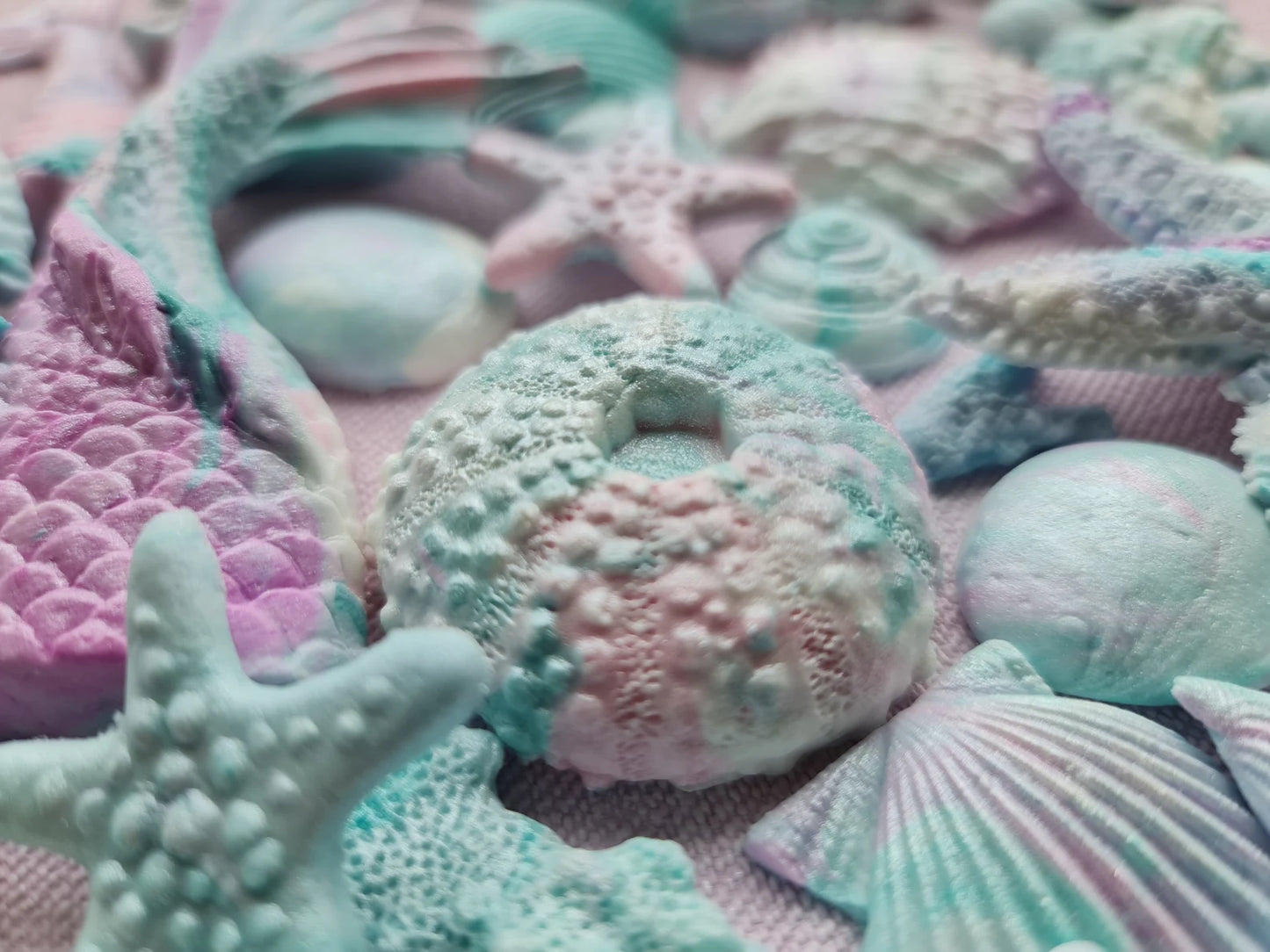 Pastel-colored fondant sea shells and starfish on a textured surface