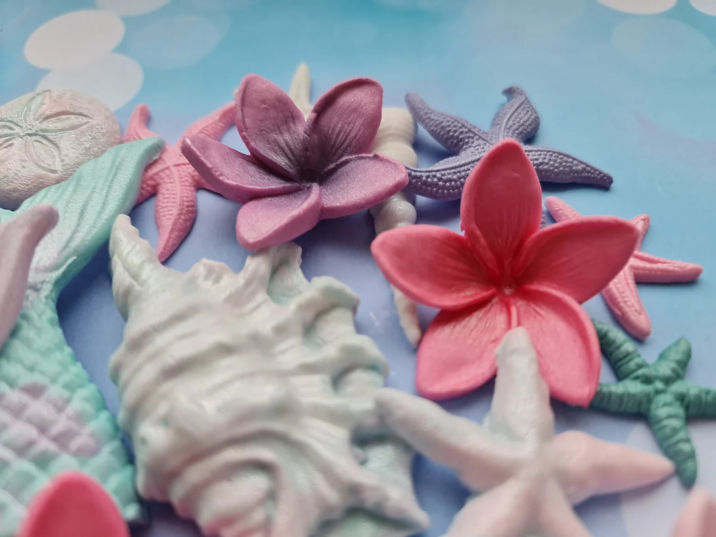 Colorful sea-themed fondant decorations including shells and flowers on a blue background
