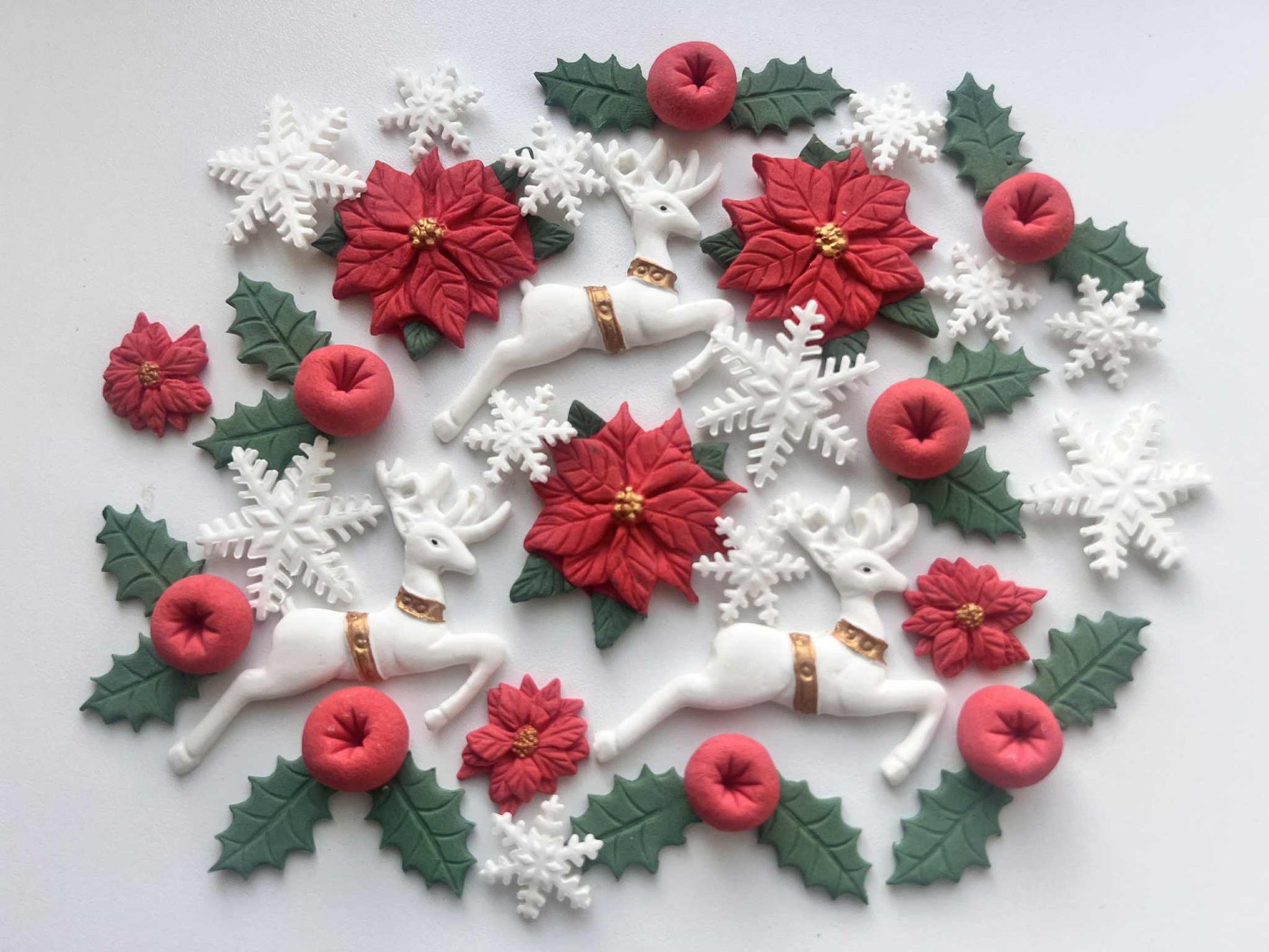 Edible Christmas fondant decorations including reindeer poinsettias holly leaves red berries and snowflakes