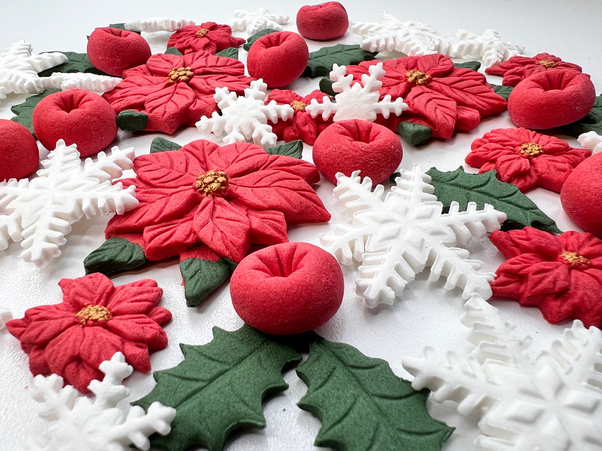 Close-up of edible fondant poinsettias, red berries and white snowflakes for cake decorating