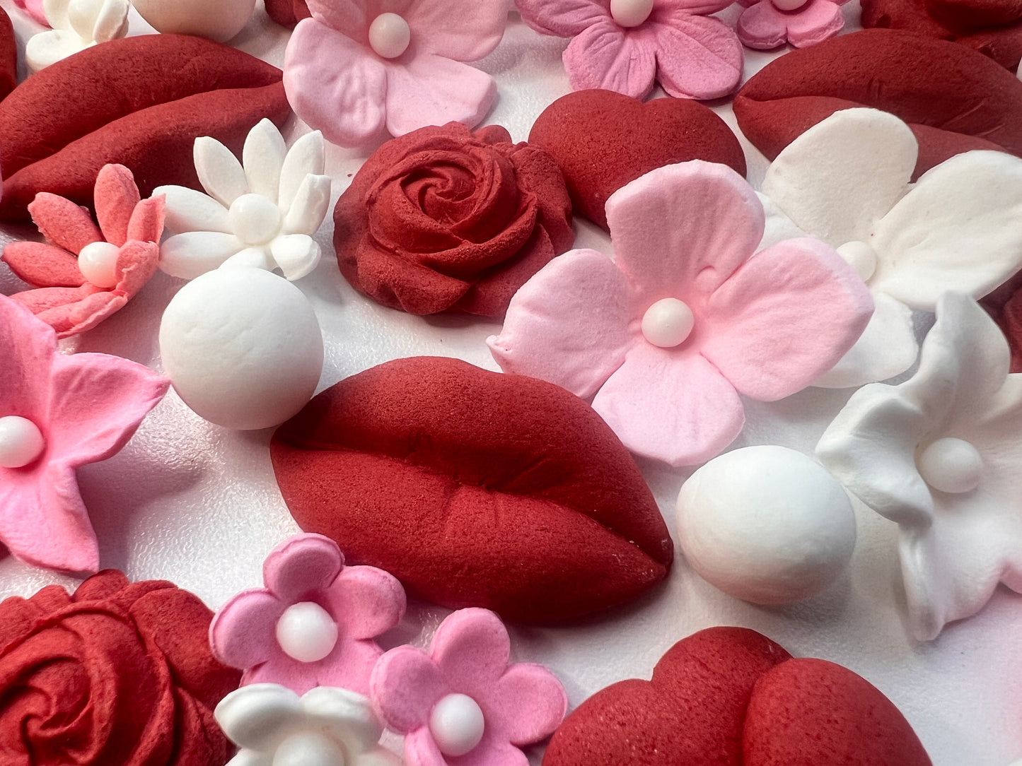 Close-up of red, pink, and white floral and lip-shaped sugar decorations cake topper.