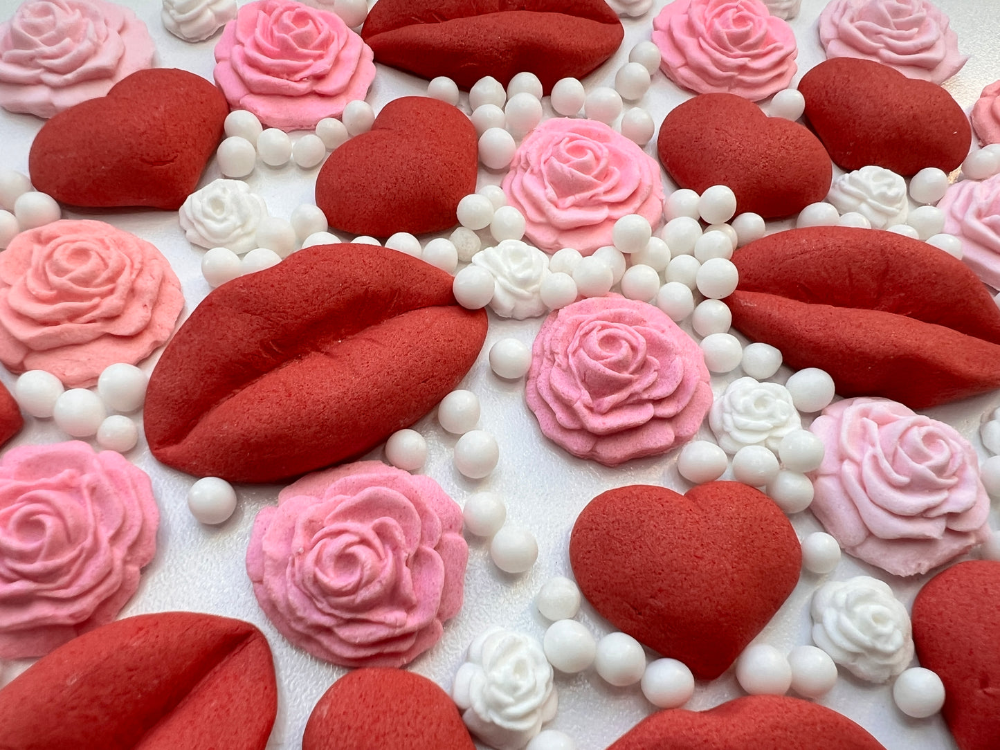 Fondant red hearts, pink roses, and white beads on a white background