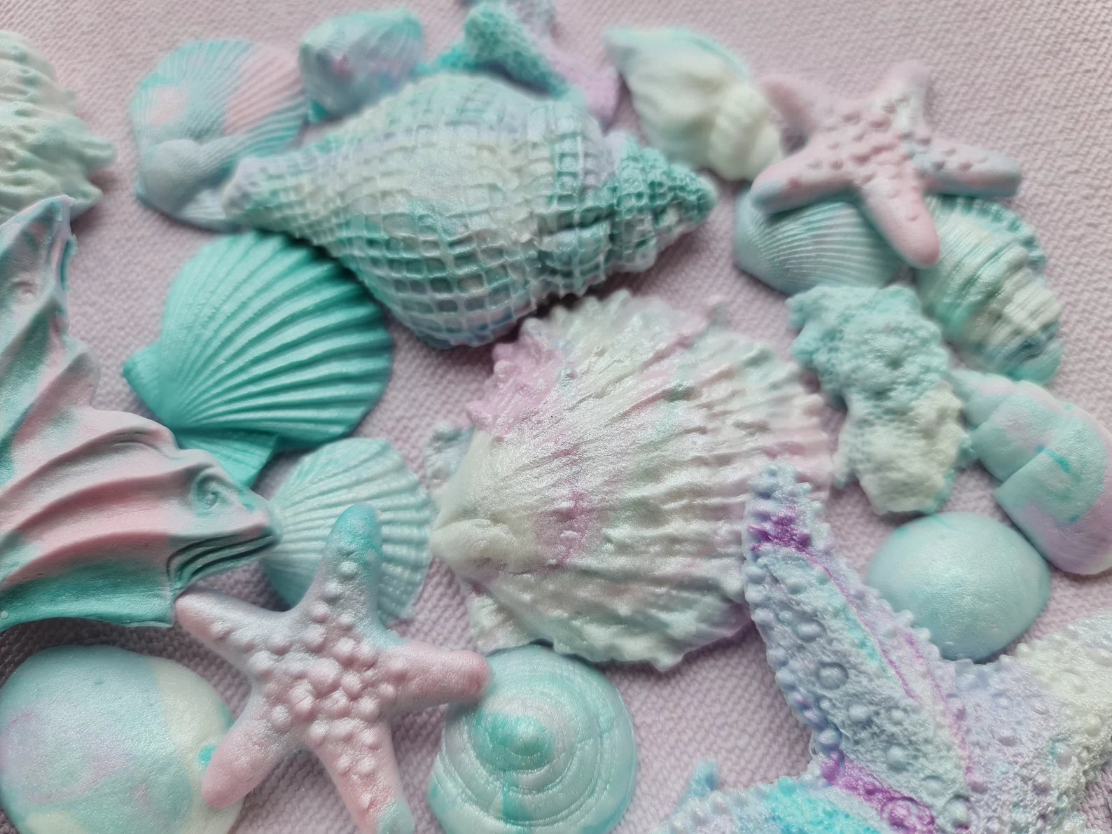 Colorful sea-themed fondant decorations including shells and starfish on a pink background