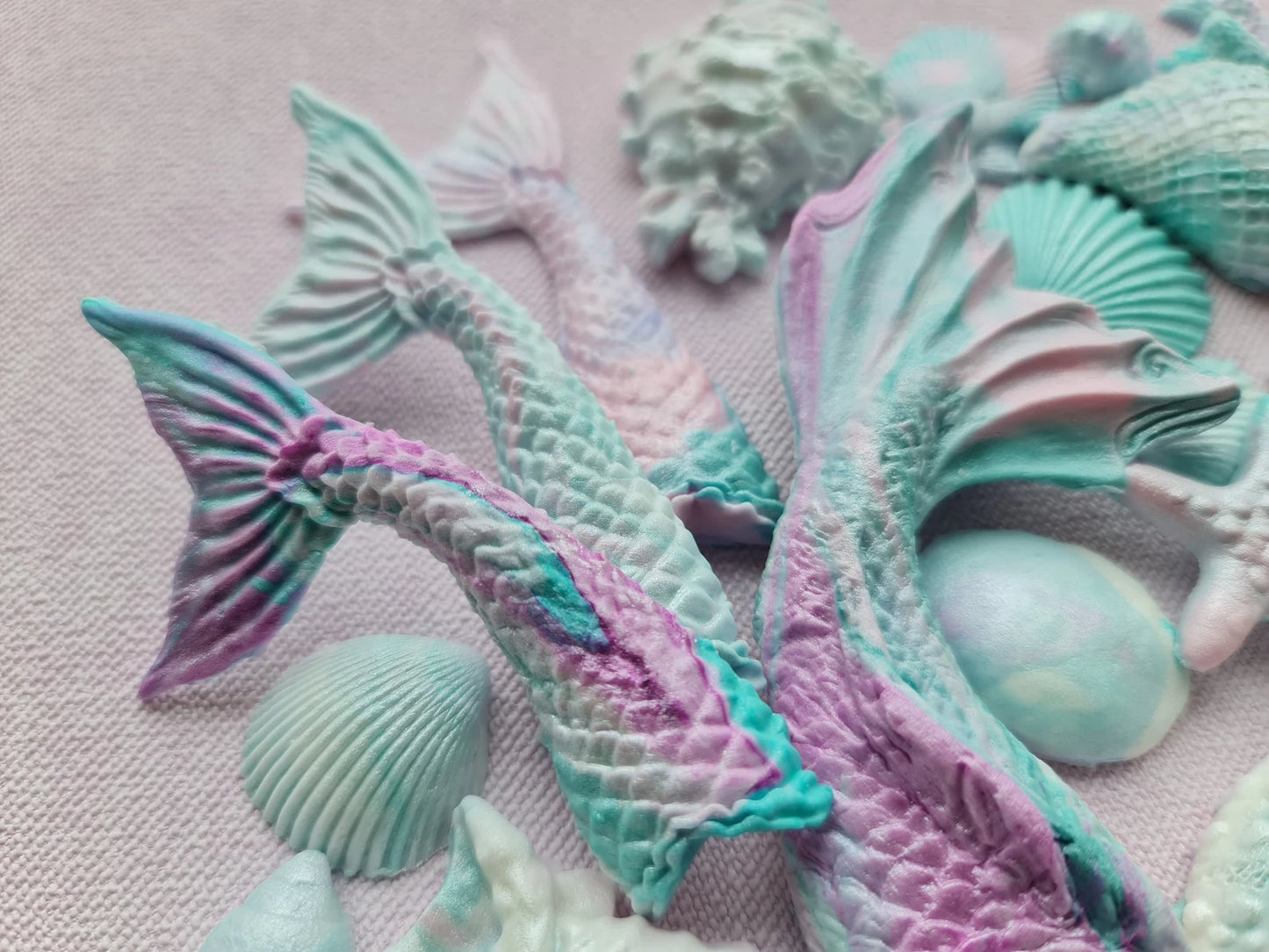 Colorful mermaid tail and seashell sugar decorations on a pink background