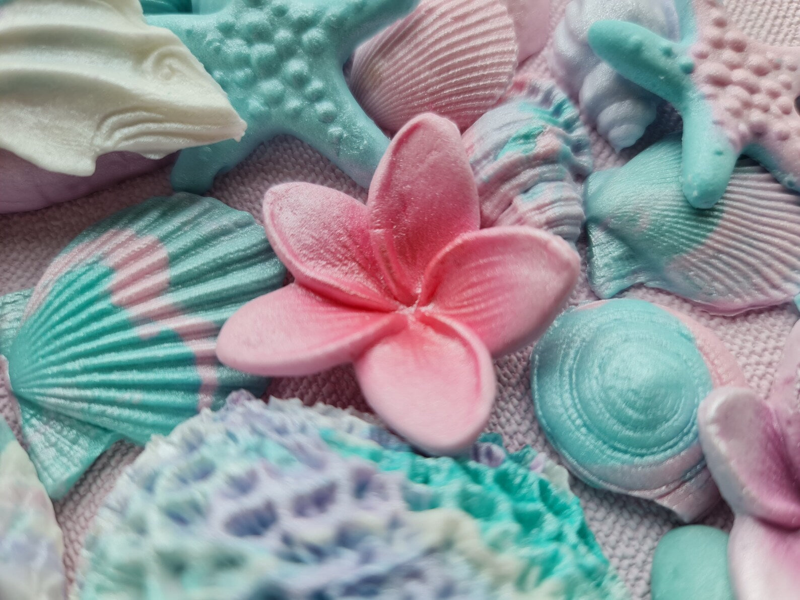 Colorful sea-themed sugar decorations: starfish, shells, and a pink plumeria.
