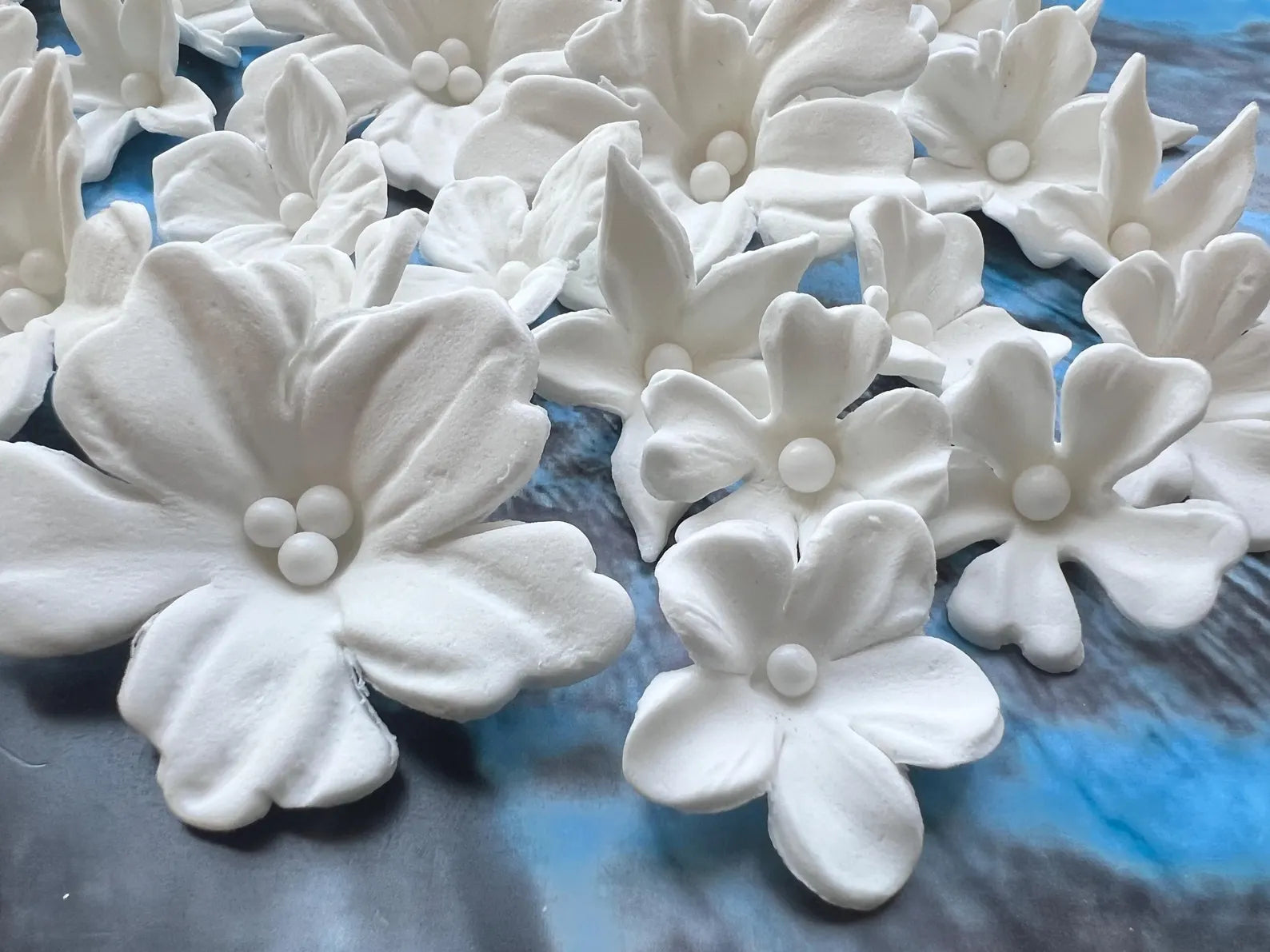 Close-up of white edible fondant flowers with detailed petals and sugar pearl centers
