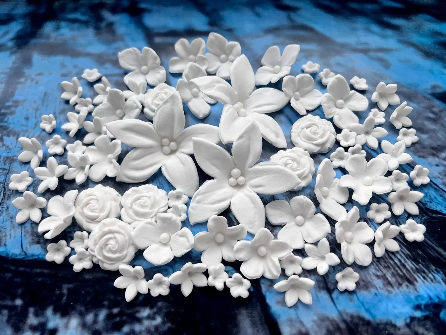 Close-up of handmade white edible fondant flowers with pearl centers for cake decorating