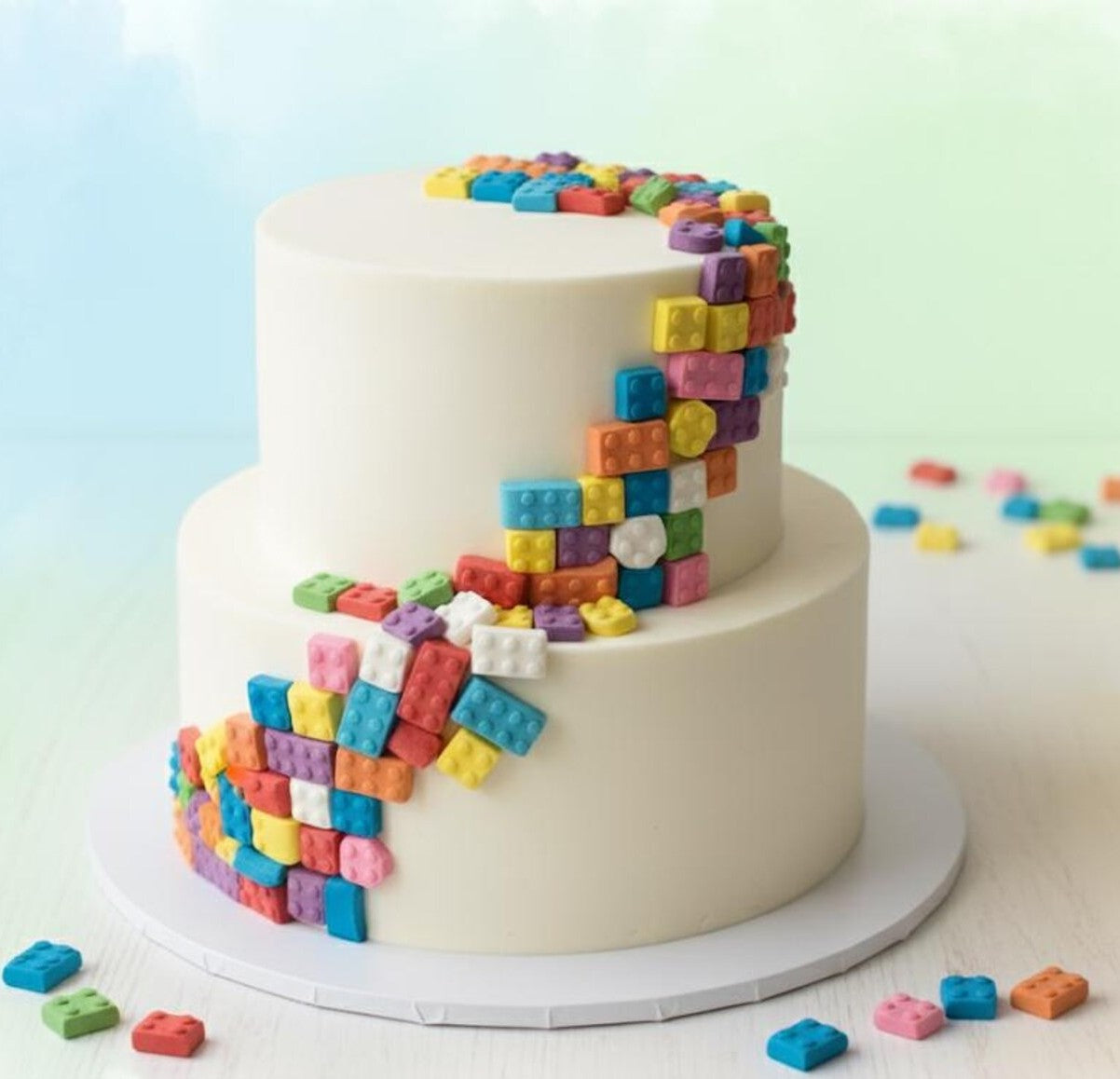 Two-tier cake with colorful sugar building block design on a light background