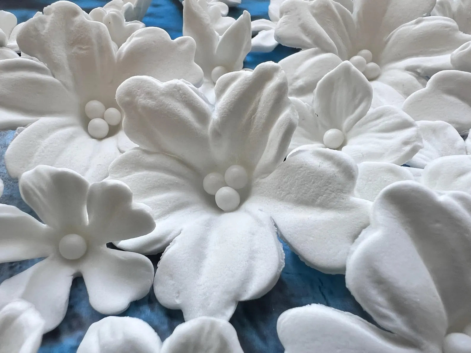 Close-up of white edible fondant flowers with detailed petals and pearl centers