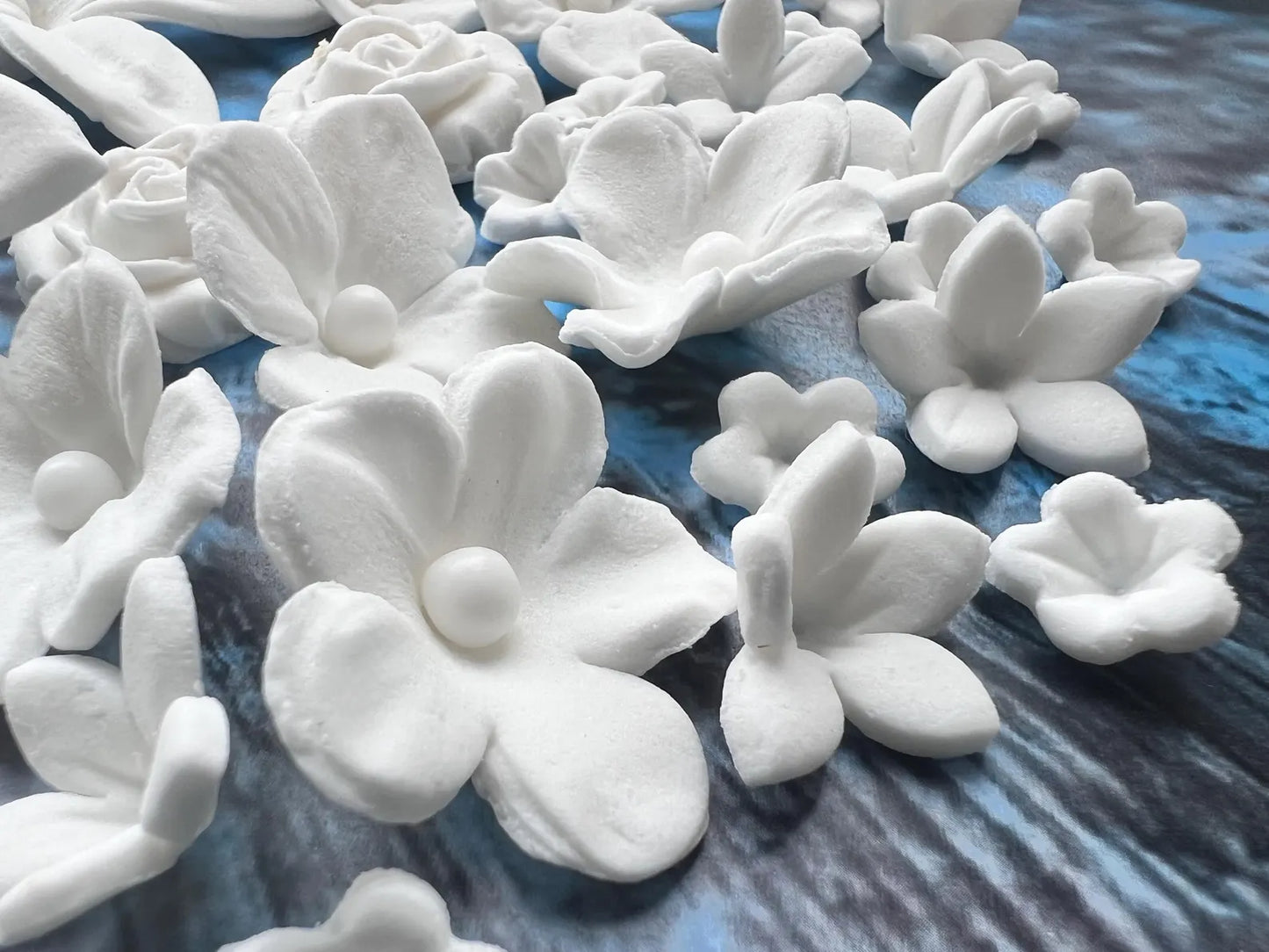 White fondant flower-shaped objects on a textured blue surface
