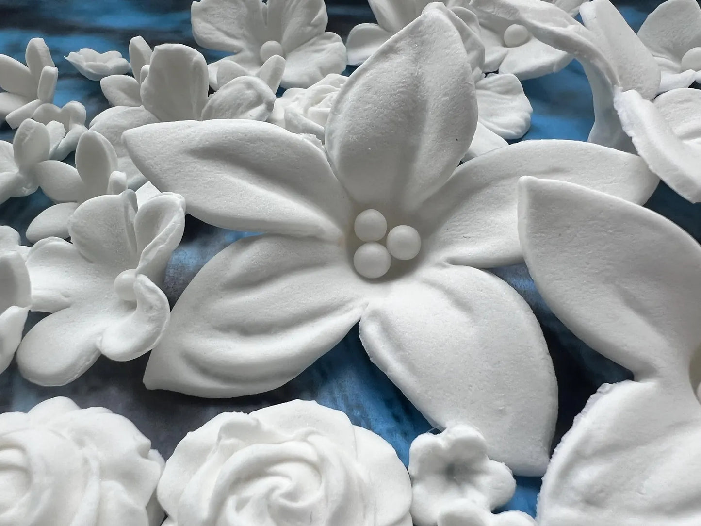 White fondant floral designs on a blue textured surface