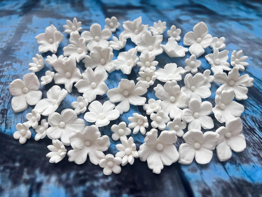 White edible fondant flower cake decorations in assorted floral shapes
