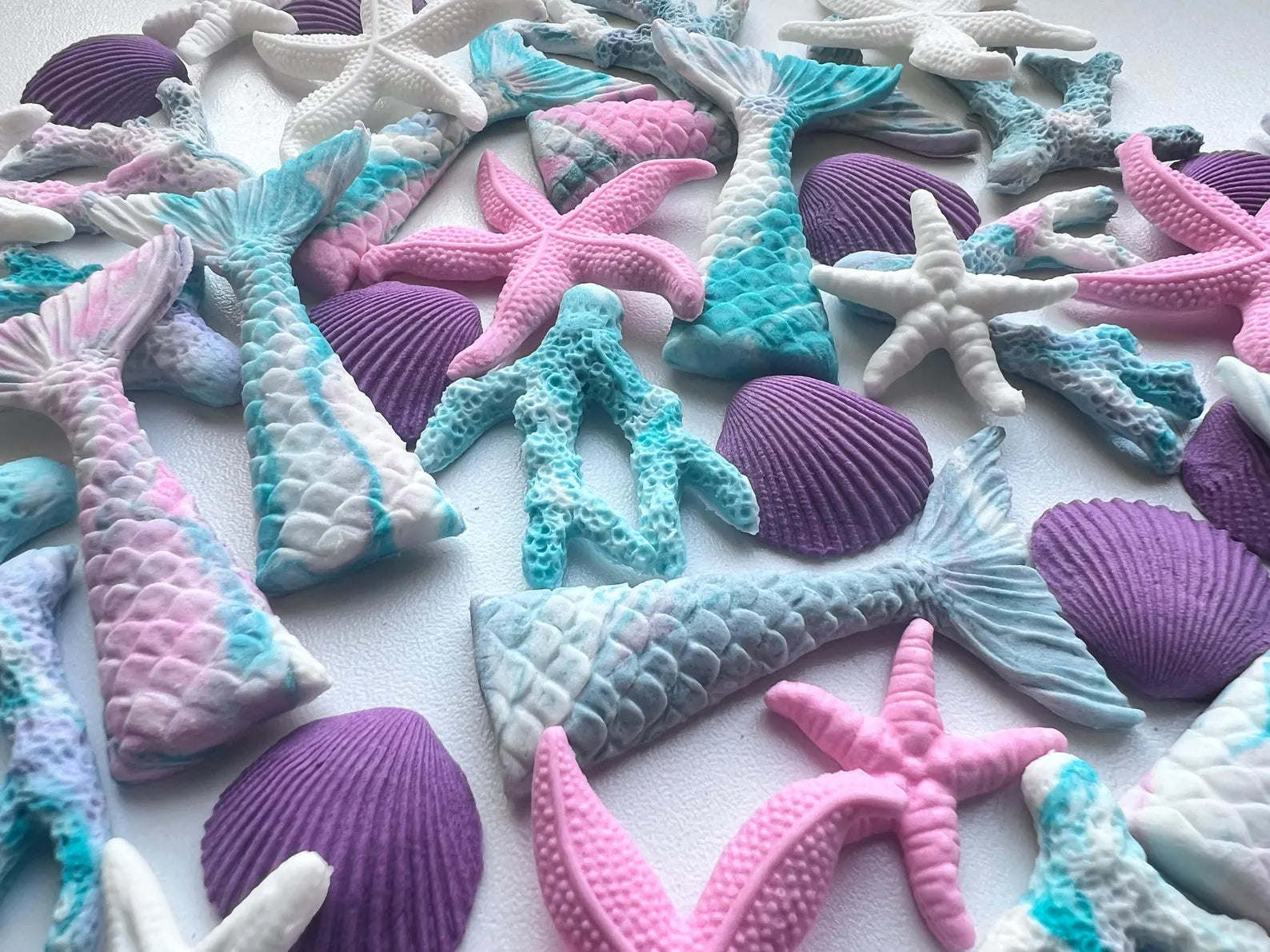 Colorful fondant mermaid tail and starfish decorations on a white background