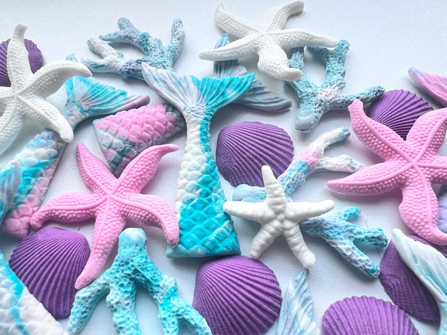Colorful sugar starfish, mermaid tails, and seashells on a white background