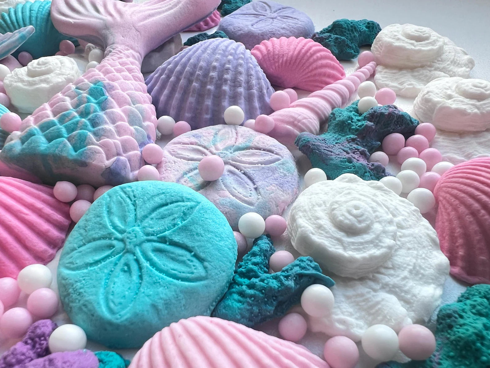 Close-up of pastel edible sea life cake decorations with shells, sand dollars, coral textures and sugar pearls
