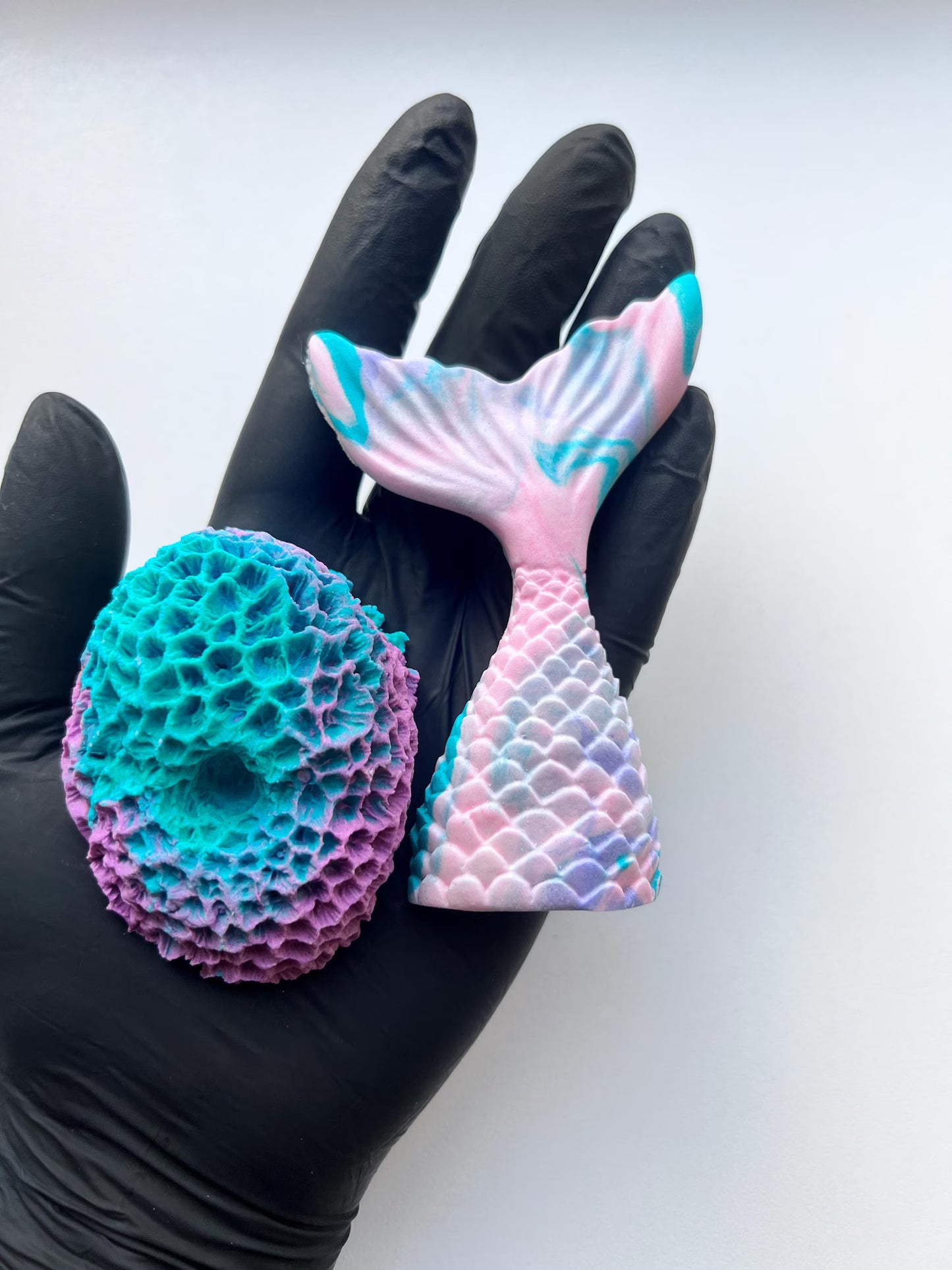 Fondant mermaid tail and large coral for cake decorating on hand with black glove. 
