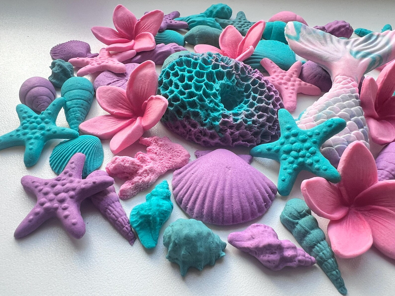 Colorful sea-themed fondant decorations including stars, shells, and flowers on a white background
