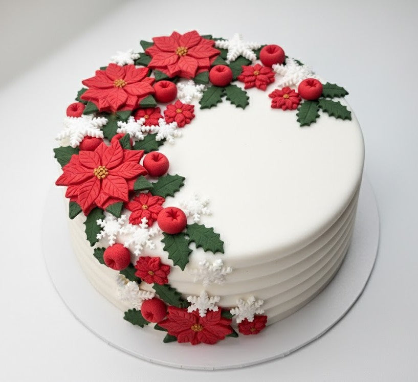 White Christmas cake decorated with edible fondant poinsettias, holly leaves, berries and snowflakes.