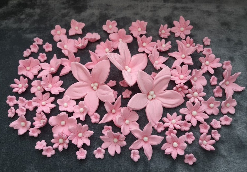 Pink sugar flower with pearl centers on a dark background