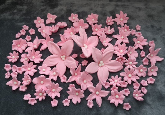 Pink sugar flower with pearl centers on a dark background