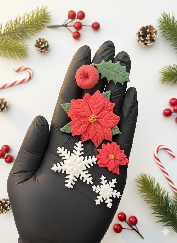Edible fondant Christmas decorations shown in hand for size reference — poinsettias, holly leaves, berries and snowflakes